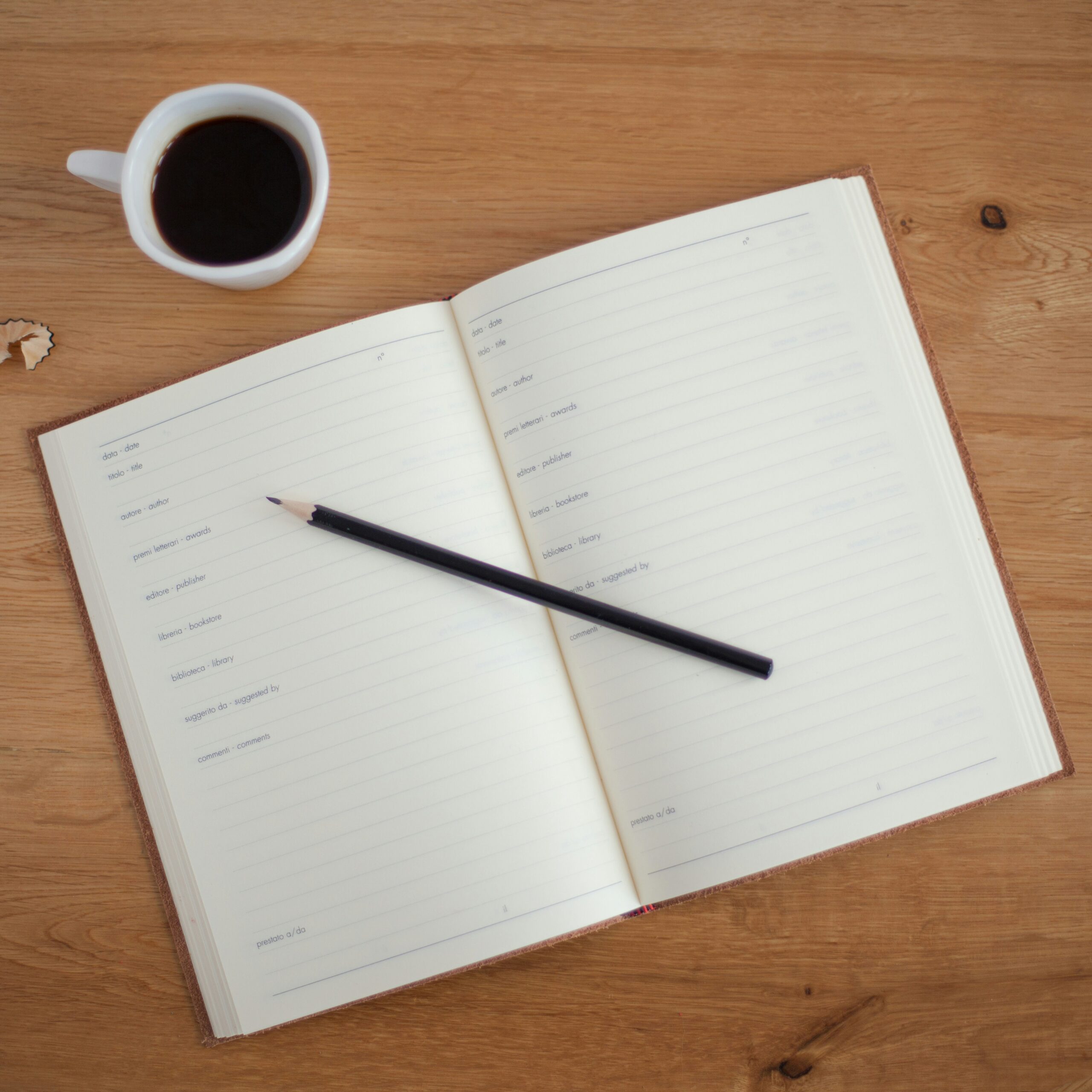 A black coffee cup near a book and a pencil over a book note for use.